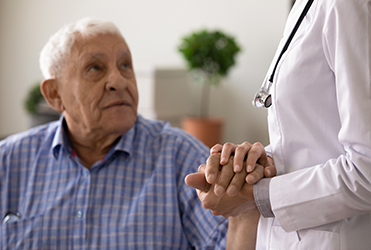 older male patient holding hands with doctor